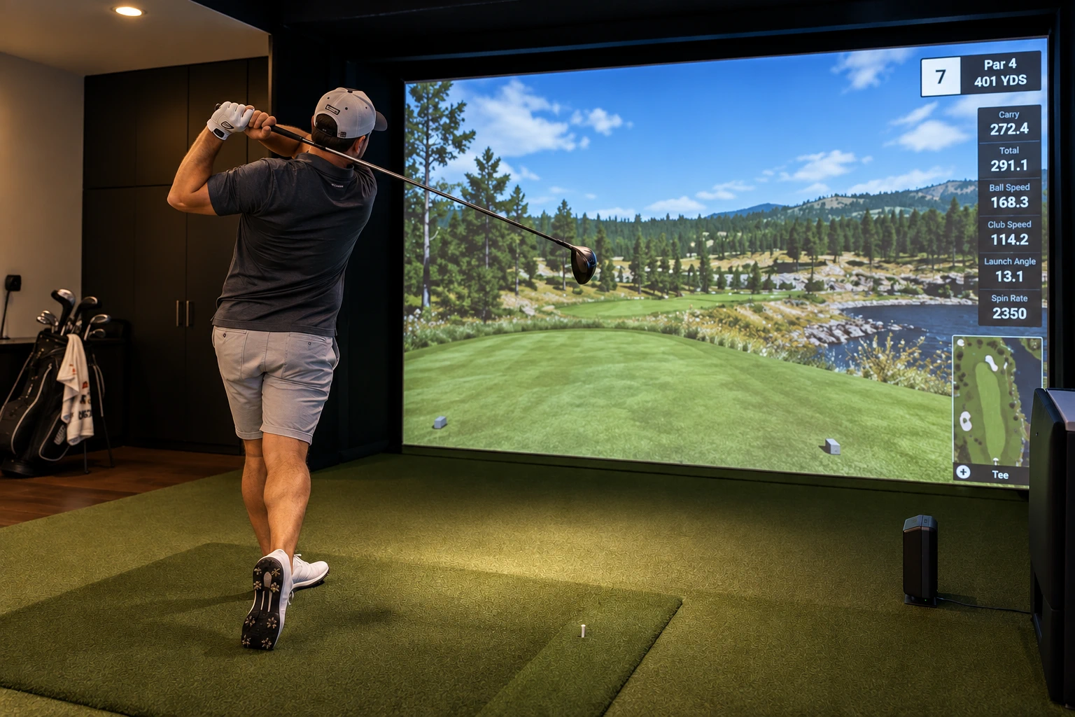 A golfer finishing a driver swing in a dark home simulator room
